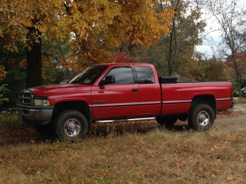 1989 Ford Bronco - Red 1994 Dodge Ram 2500 pickup truck parked in grassy area with autumn leaves overhead.