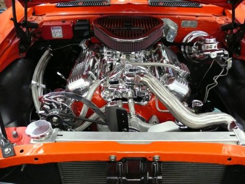 1968 Chevrolet Camaro - The engine bay of a 1968 Chevrolet Camaro shows a polished V8 engine with chrome accents and an orange exterior.