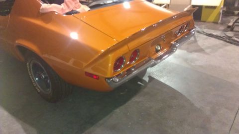1973 Chevrolet Camaro - The rear of an orange 1973 Chevrolet Camaro is visible, dual taillights and a chrome bumper.