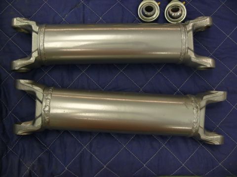1976 Chevrolet Corvette - Two driveshafts and two u-joints are laid out on a blue quilted surface. The registry claims this is a 1976 Chevrolet Corvette, but the ima…