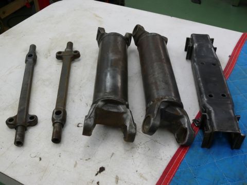 1976 Chevrolet Corvette - A collection of driveshaft parts, including yokes and shafts, are displayed on a white surface.