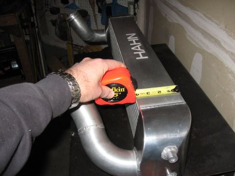 1995 Ford Bronco - A hand holds an orange tape measure to an intercooler with 'HAHN' branding visible.