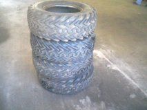 1992 Ford Bronco - Four ATV tires are stacked on a concrete surface, showing their worn tread.