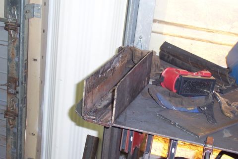 1996 Ford Bronco - A hand-fabricated sheet-metal box with visible weld seams and surface rust sits on a metal shelf or workbench, alongside a red-and-black we…