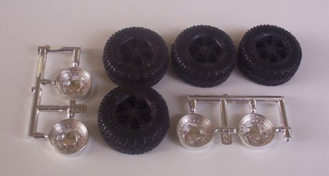 1992 Ford Bronco - Four model tires and two sets of chrome rims are laid out on a white surface.