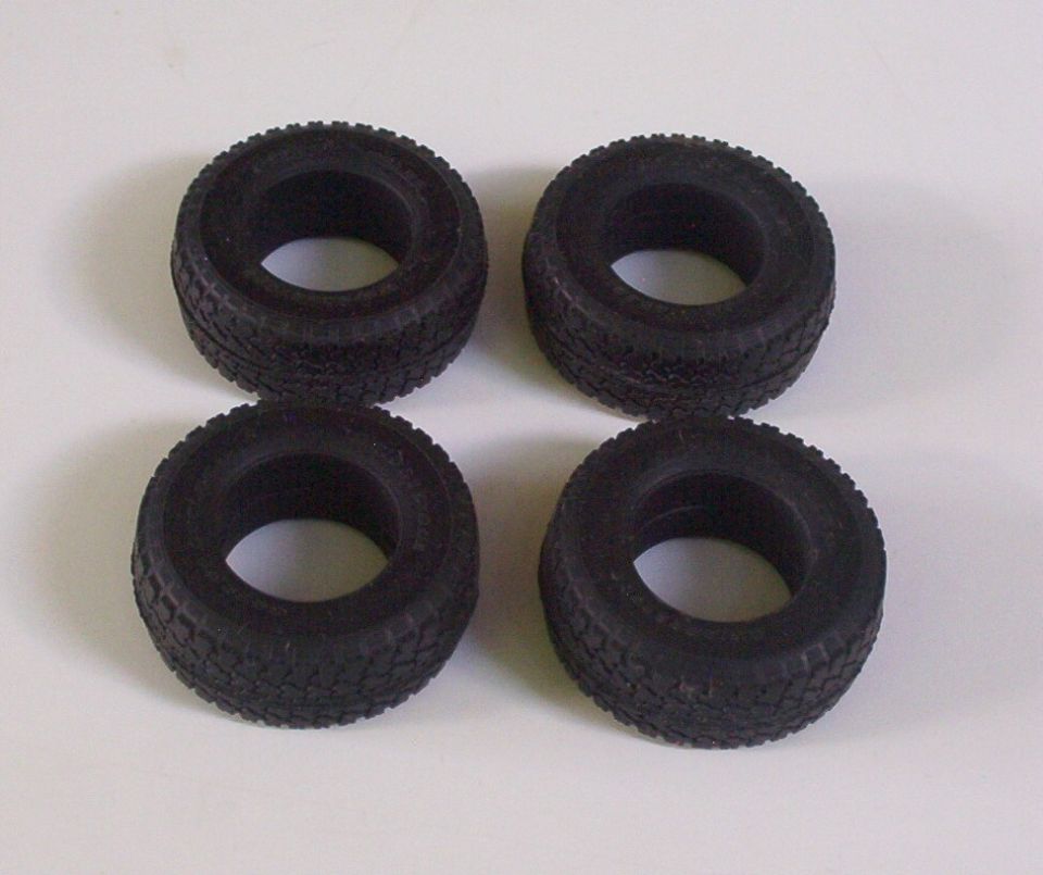 Four black rubber tires with aggressive tread patterns, arranged in a two-by-two grid on a white surface