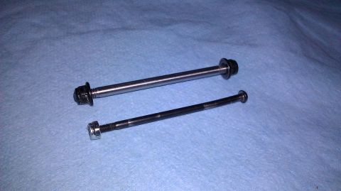 1996 Ford Bronco - Two bolts, one longer and silver, the other shorter and black, are laid out on a blue textured surface.
