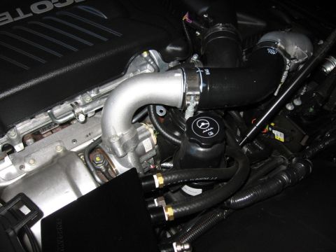 1995 Ford Bronco - Close-up of an engine bay, showing various components and hoses, with a black cap a steering wheel emblem.