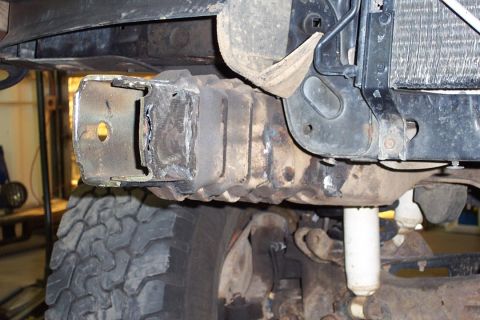1996 Ford Bronco - Underside view of a vehicle's front frame section showing a welded steel bracket or frame horn with a mounting hole, positioned above a mud…