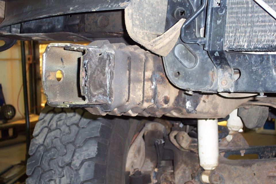 Underside of vehicle frame with welded bracket, tire, shock and radiator visible