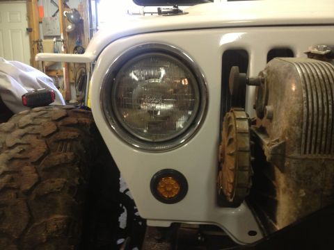 2000 Jeep TJ - Close-up of a 2000 Jeep TJ's front fender, showing the headlight and a large off-road tire.