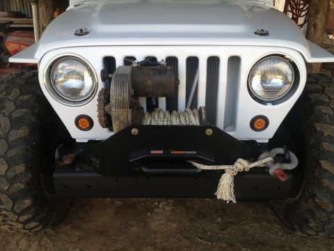 2000 Jeep TJ - Front view of a white Jeep TJ, showing its grille, headlights, and a winch with rope.