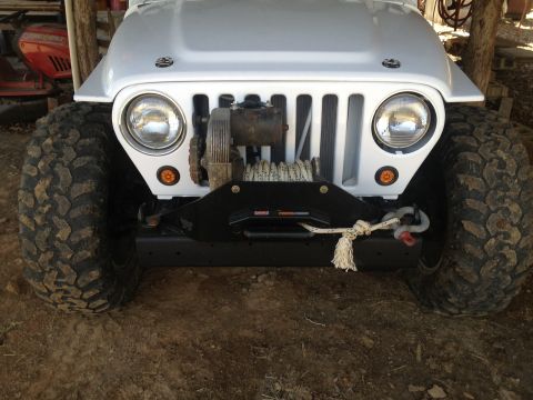 2000 Jeep TJ - Front view of a white Jeep Wrangler with large off-road tires and a winch mounted on the bumper.