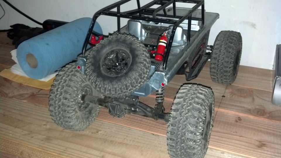 Remote control rock crawler toy with large tires and a roll cage, seen from the rear