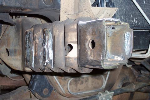 1996 Ford Bronco - Close-up underside view of a frame or crossmember with fresh weld beads joining reinforcement plates to a boxed steel bracket, surrounded b…