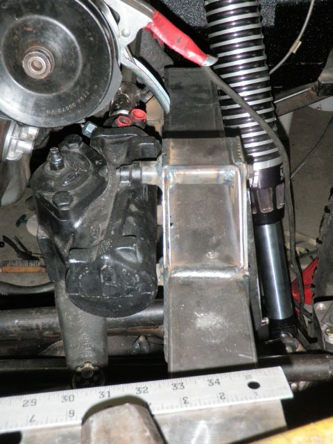 1961 International Scout 800 - Close-up view of a steering gear box and power steering pump assembly, with a custom metal bracket attached.