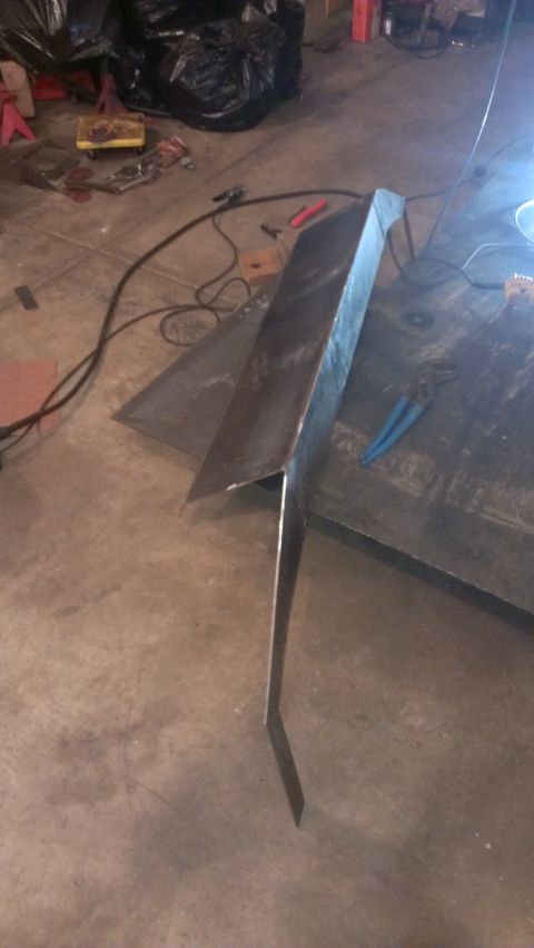 1995 Ford Bronco - A metal component, possibly a custom fabrication, rests on a workshop floor with tools and debris nearby.