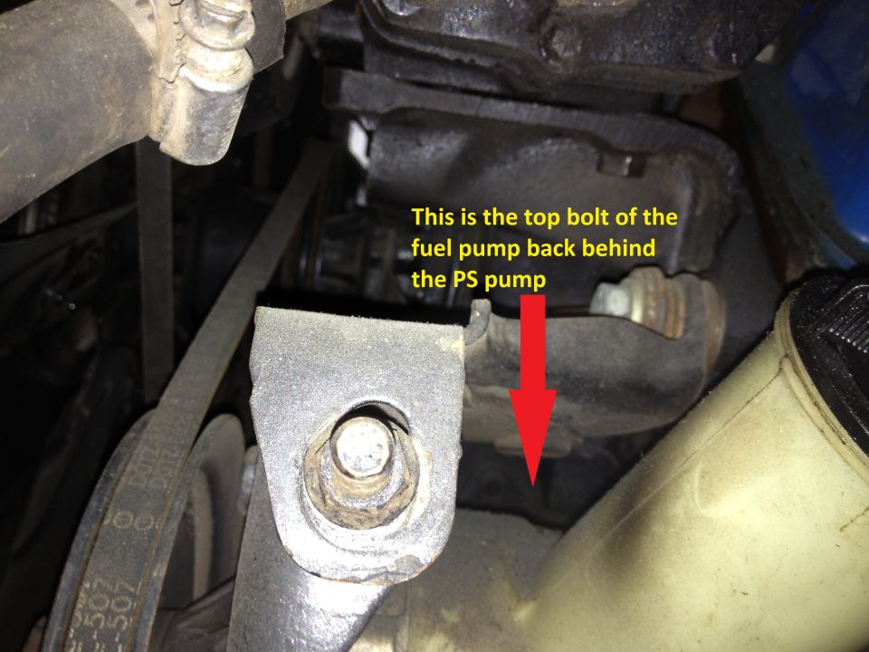 Close-up of engine component with red arrow pointing to fuel pump bolt