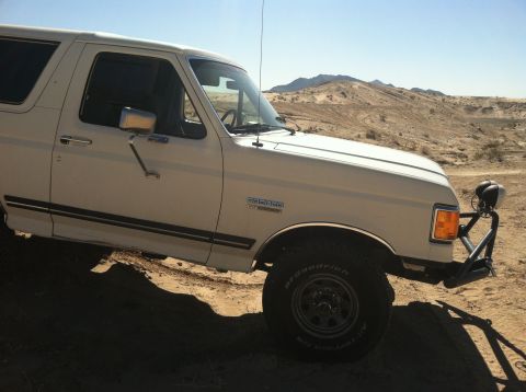 1989 Ford Bronco - White 1989 Ford Bronco parked in a desert with mountains in the background.
