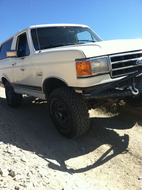 1989 Ford Bronco - This SUV is parked on a dusty, uneven surface with a clear blue sky overhead.