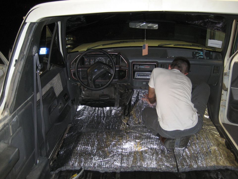 Man installing sound deadening material on the floor of a 1989 Ford Bronco interior