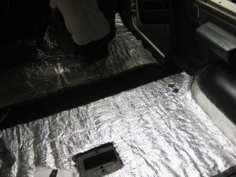 1989 Ford Bronco - The interior floor of a vehicle is covered with silver insulation material, with a person kneeling in the background.