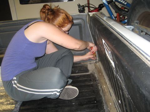 1989 Ford Bronco - Woman works on an interior panel, possibly in a truck bed or cargo area.