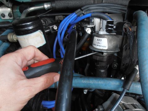 1990 Ford Bronco - Working on a Ford EVP sensor with a screwdriver, showing engine components and hoses.