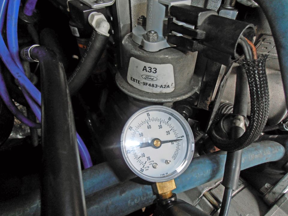 Close-up of a Ford A33 sensor with a pressure gauge attached, showing readings