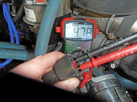 1990 Ford Bronco - A multimeter is used to test a sensor in the engine bay, displaying a voltage reading.