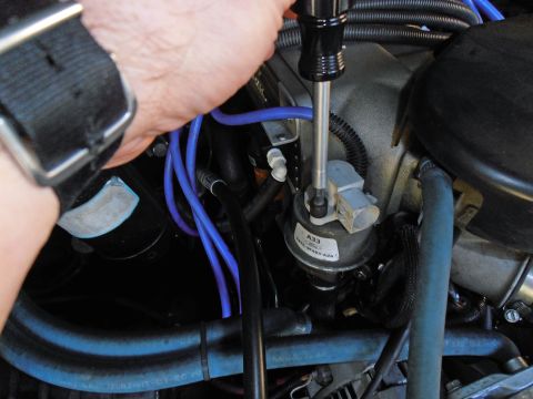 1990 Ford Bronco - A mechanic works on an EVP sensor, part of a vehicle's engine system.