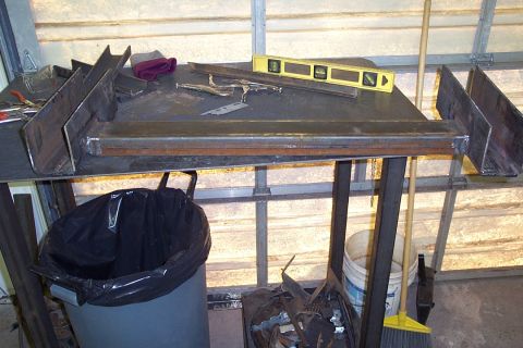 1996 Ford Bronco - A metal fabrication workbench in a garage or shed, topped with a yellow bubble level, metal brackets, scrap steel pieces, and a rag. Below…