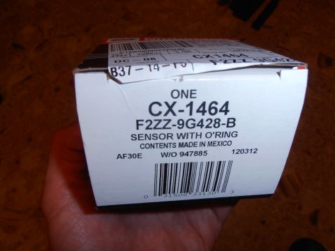 1990 Ford Bronco - A hand holds a box containing a sensor with an O-ring, part number CX-1464.