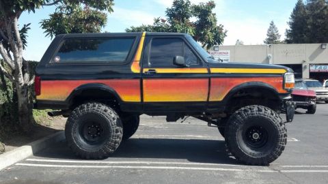 1994 Ford Bronco - This modified SUV has a distinctive sunset-style paint job and is equipped for off-road use.