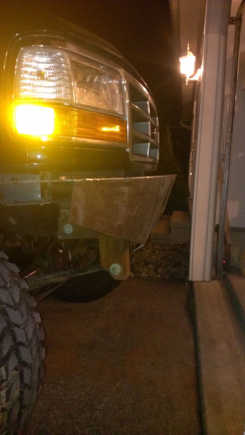 Front of a Ford truck with a custom bumper. Headlight and grille are visible