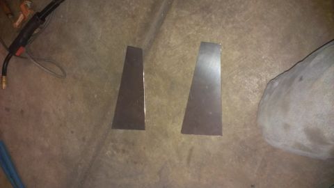 1995 Ford Bronco - Two metal brackets and a welding torch lie on a concrete floor, suggesting a fabrication project.