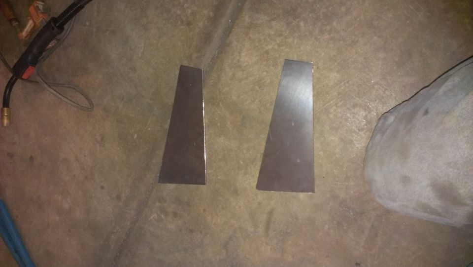 two metal brackets on concrete floor next to welding torch