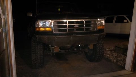 1995 Ford Bronco - Front view of a black 1995 Ford Bronco a custom metal bumper and large off-road tires.