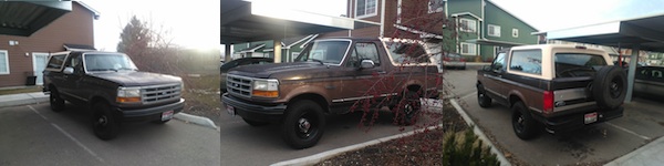 Front view of a dark brown 1992 Ford Bronco parked under a carport. The vehicle has black wheels and a tan top