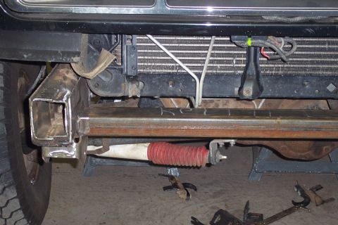 1996 Ford Bronco - Underside front view of a Ford Bronco showing the front axle, a red-booted steering damper or shock, tubular crossmember, and radiator/cond…