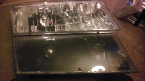 2000 Mercury Grand Marquis - A close-up view of two vehicle headlights, one in better condition than the other.