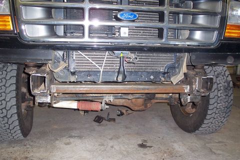 1996 Ford Bronco - Front-end view of a Ford truck with the front bumper removed, showing the exposed frame horns, chrome grille with blue Ford oval, amber tur…