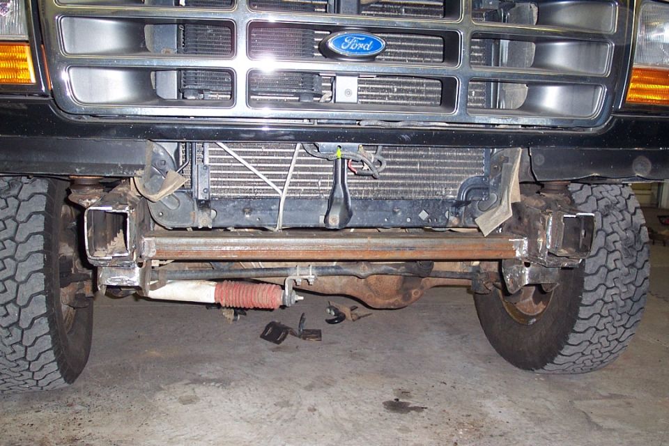 Front of Ford truck with bumper removed showing frame horns and grille in garage