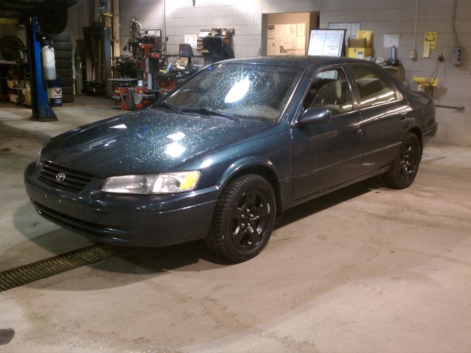 Dark green 1998 Toyota Camry parked inside a garage with black rims