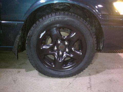 1998 Toyota Camry - Close-up of a black wheel and tire on a dark green vehicle. The registry claims it is a 1998 Toyota Camry, but this is not verifiable from…