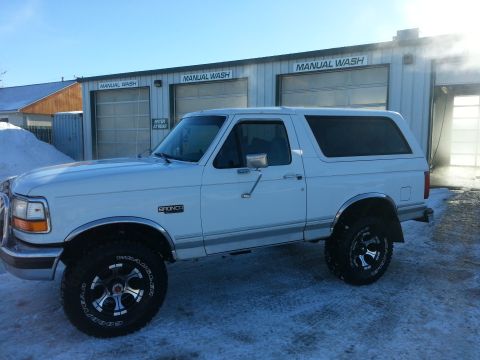 1994 Ford Bronco - A white 1994 Ford Bronco is parked in front of a manual car wash on a snowy day.