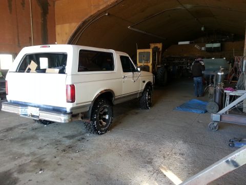 1994 Ford Bronco - A white Ford Bronco is parked inside a garage, with a yellow loader visible in the background.