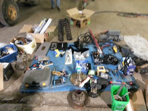 1994 Ford Bronco - Various automotive parts and tools are spread out on a blue tarp, with a large tire visible in the background.