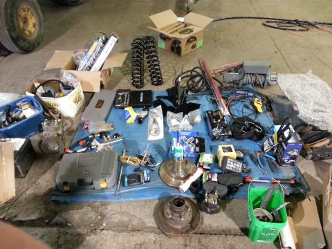 1994 Ford Bronco - Various automotive parts and tools are laid out on a blue tarp on a concrete floor.