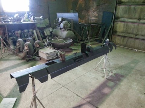 1994 Ford Bronco - A black metal automotive part is mounted on stands in a workshop environment.